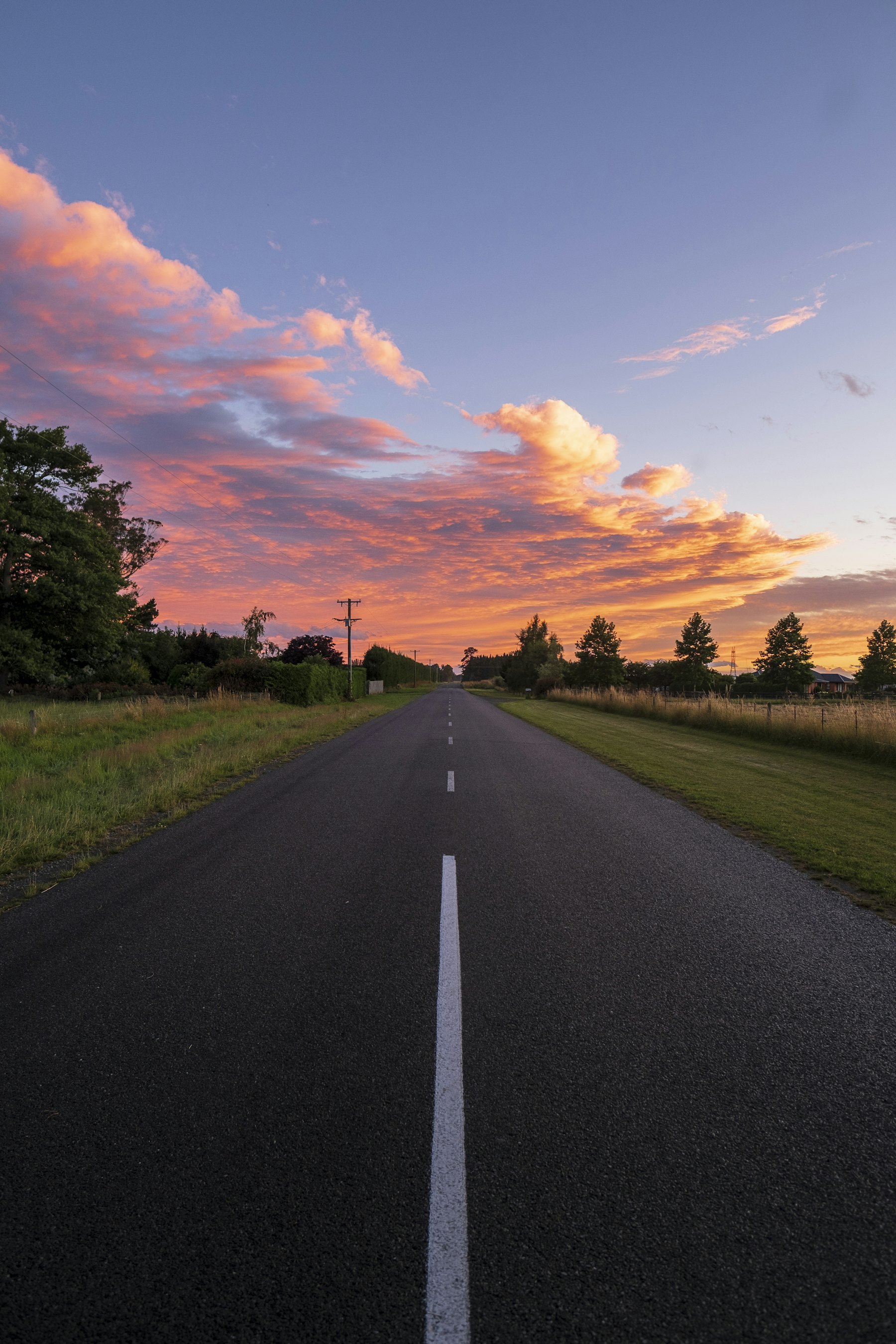 Route traversant des champs sous un grand ciel